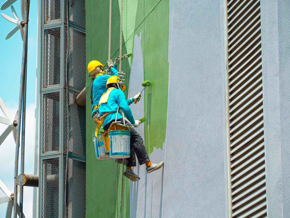 Two painters are painting the exterior of the building in Suffolk, NY.