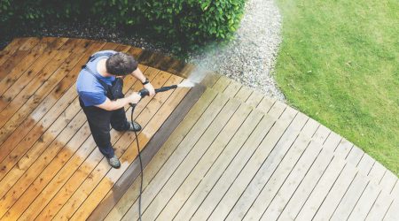 A man is cleaning a terrace with a power washer using high-pressure water in Suffolk, NY.