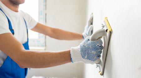 Wall plastering in Suffolk County, NY—gloved hand using trowel during renovation.